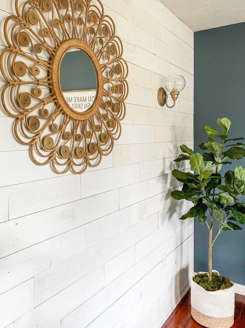 Decorative round mirror on a white horizontal plank wall
