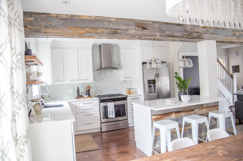 Wood-clad beam framing an opening into a white kitchen