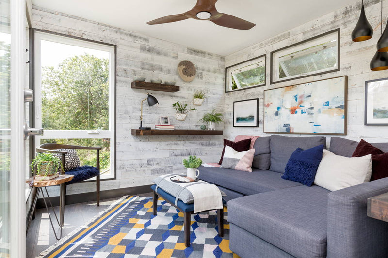 Bright sitting room with a pale wood plank wall and floating shelves