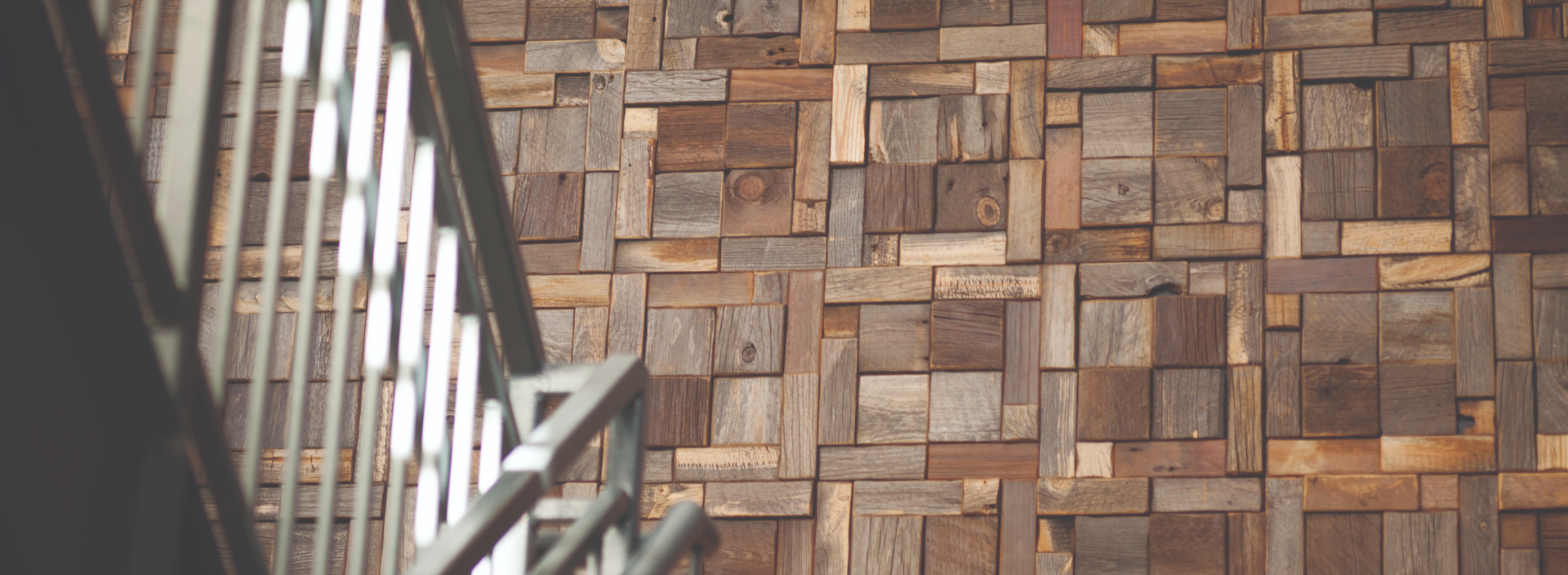 Close-up of a natural wood plank accent wall with varied tones and textures beside a metal railing