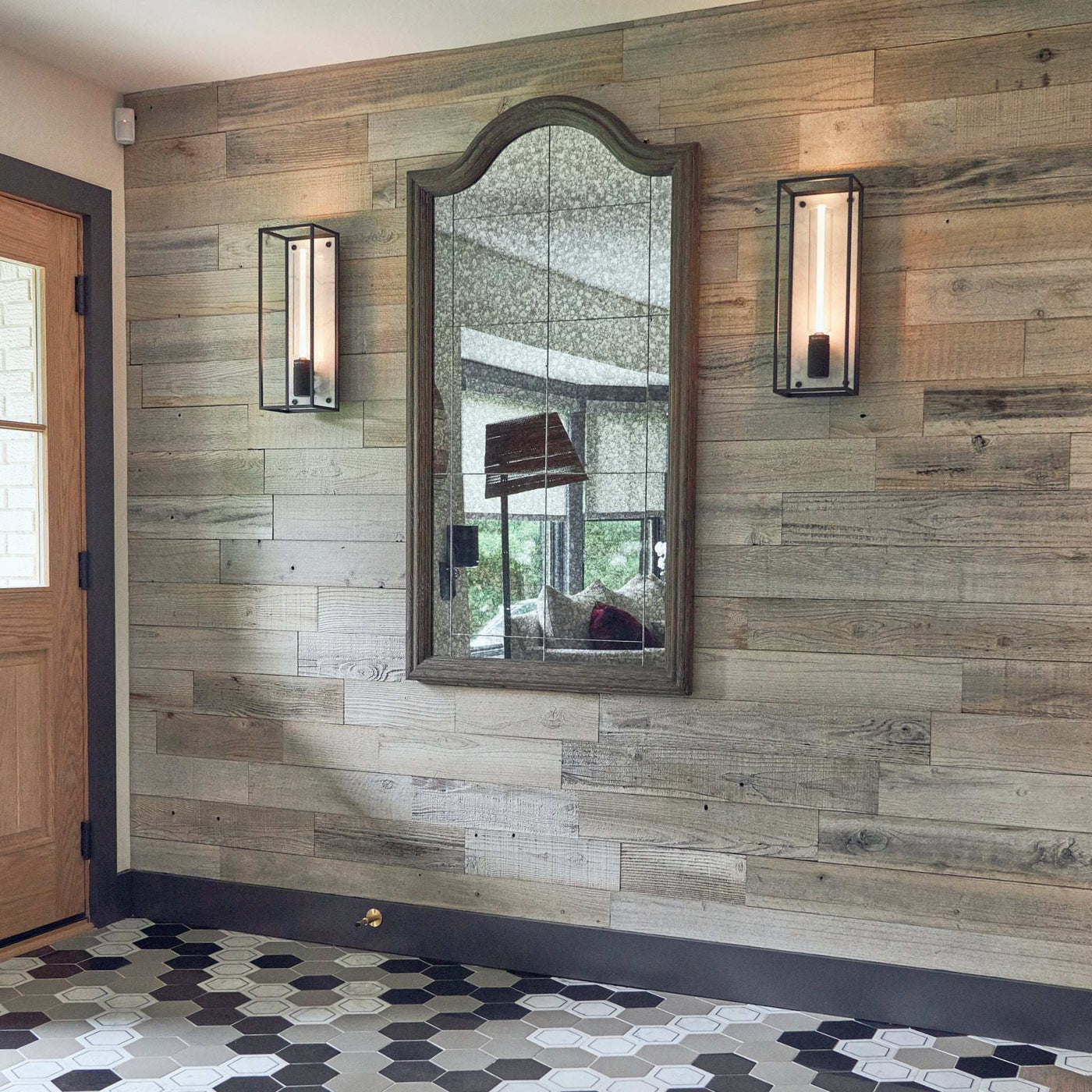 Hallway with Silvermyst Peel & Stick Wood Wall Planks, mirror, sconces, and hexagon tile floor