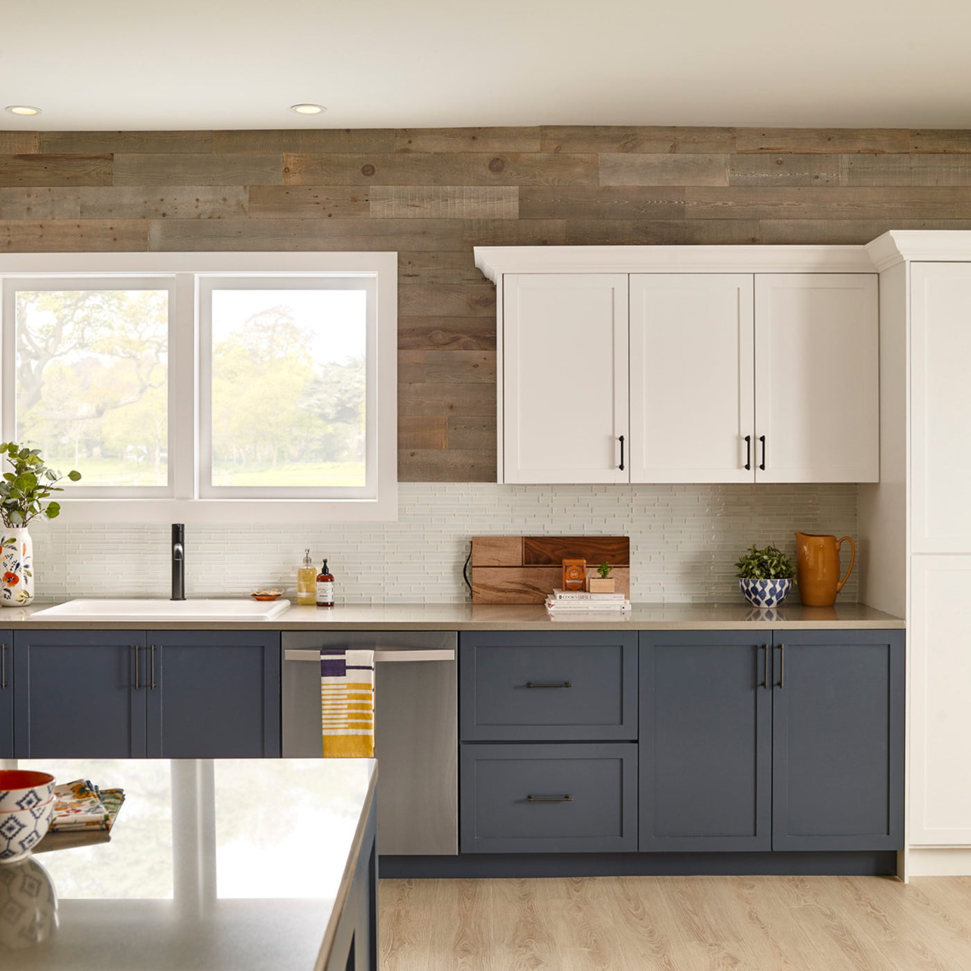 Kitchen with Cobblestone Stikwood planks above white cabinets and a window