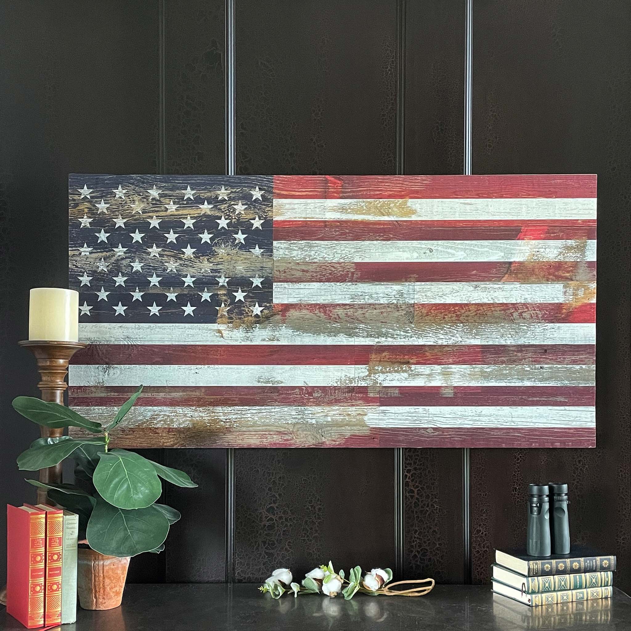 Reclaimed Weathered Wood U.S. Flag above a mantle with books, a candle, and a potted plant