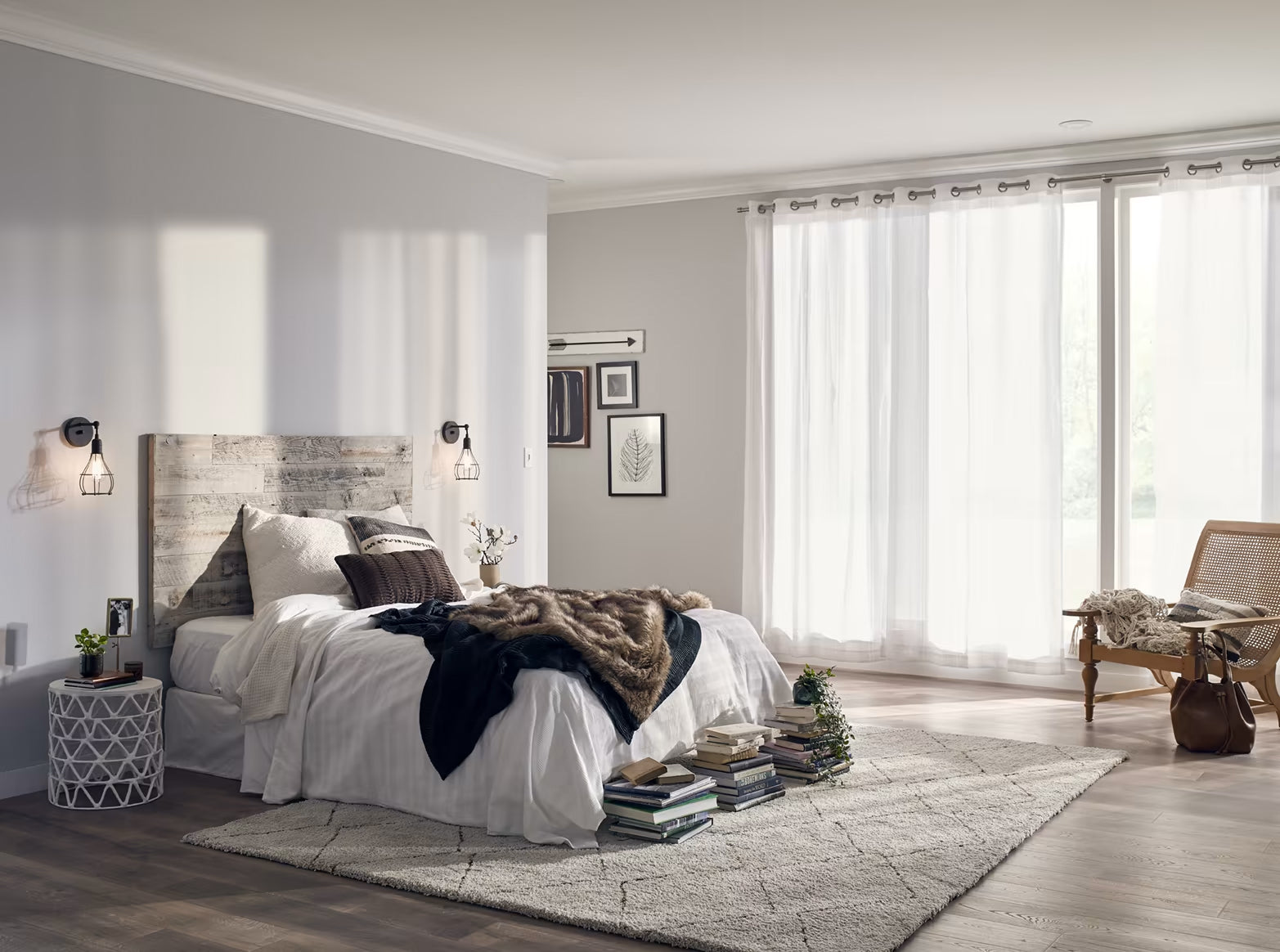 Bright bedroom with natural light, white bedding, wood plank headboard, cozy rug, and sheer curtains on large windows