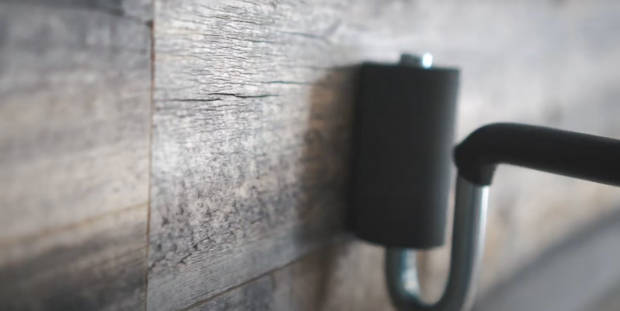 Close-up of natural real wood plank wall with blurred matte black metal fixture in cozy setting