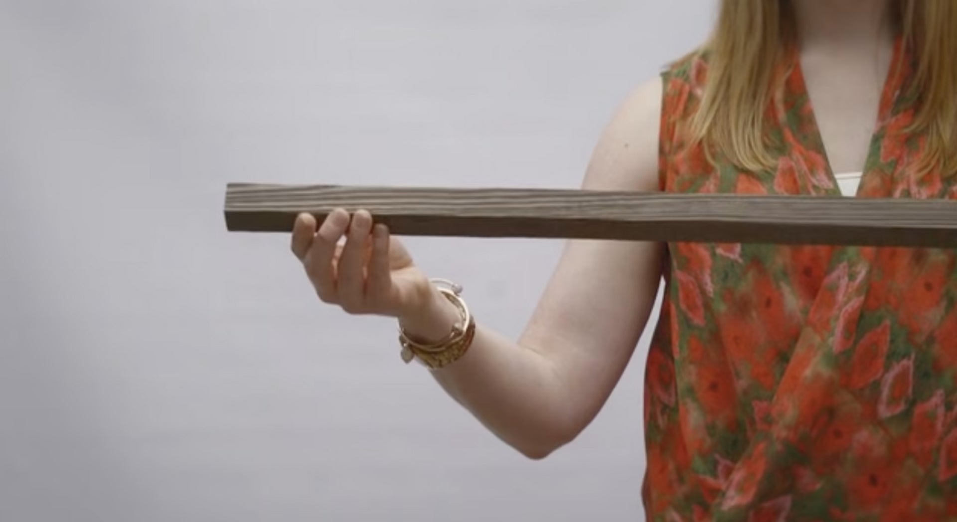 Woman holding a long natural wood plank showcasing the texture for a peel and stick real wood project